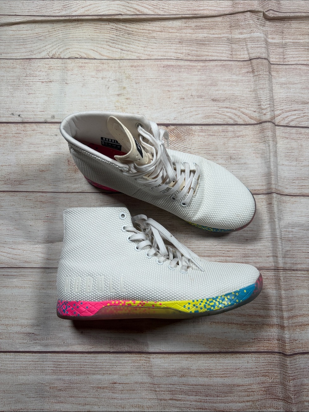 NOBULL white high-top trainers featuring a vibrant multi-color glitch sole